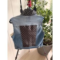Back view of size Medium light wash denim vest with contrast black and cream repeating pattern back panel