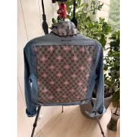 Back view of medium light-wash denim jacket with patterned panel and pink bee motifs