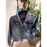 Front view of medium light-wash denim jacket with gray and pink bee-patterned collar and cuff
