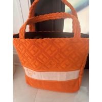 Bright orange towel-textured geometric tote with padded handles and a wide cream woven stripe
