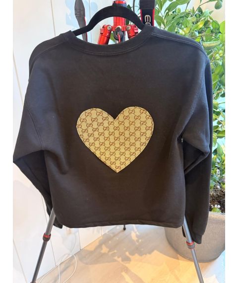 Back of black reworked jacket with large beige patterned heart applique