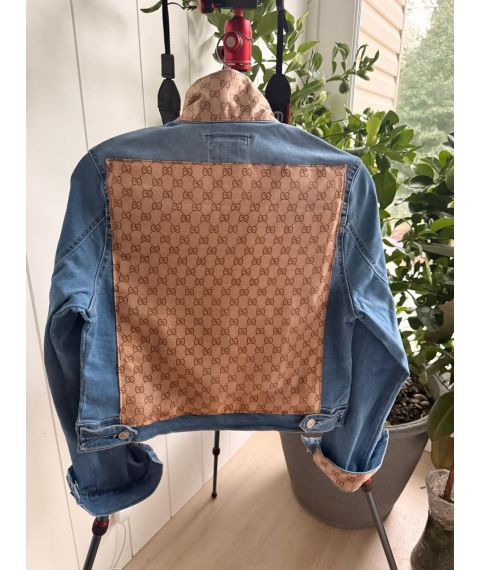 Back of medium blue denim jacket with large sand colored repeating pattern textile panel