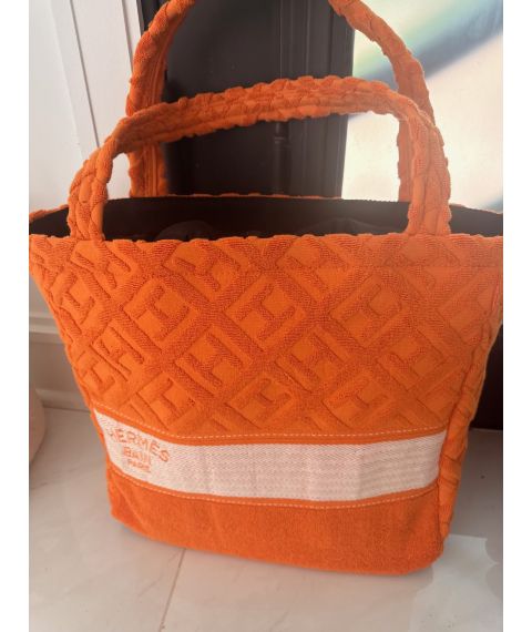 Bright orange towel-textured geometric tote with padded handles and a wide cream woven stripe